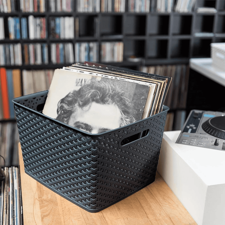 large storage basket in bedroom filled with vinyl records beside record player