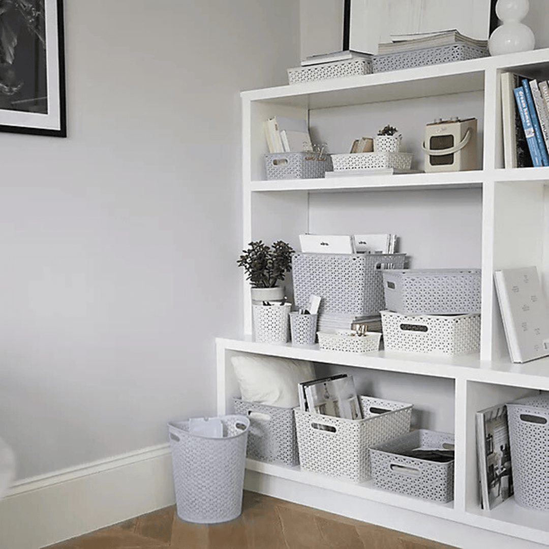 waste paper basket bin in office space with paper inside in front of shelves with curver storage baskets and bins 