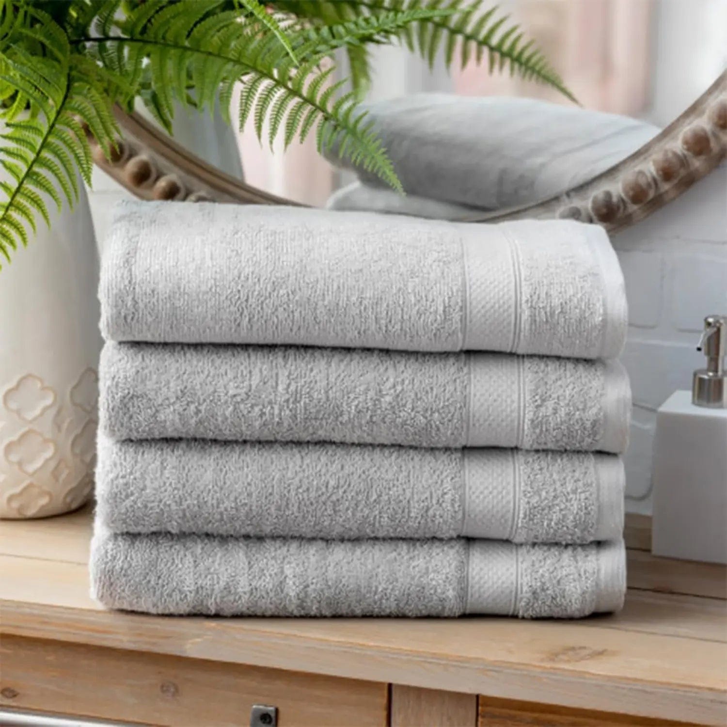 4 silver grey towels on a bathroom dresser with mirror and fern plant