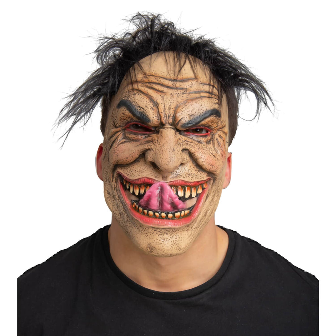 A person wearing a creepy, distorted monster mask with wild black hair, a wrinkled beige face, red eyes, and an exaggerated open grin showing pink tongue and yellowed teeth, against a plain white background.