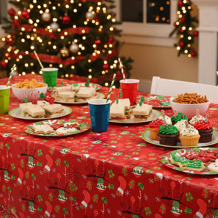 Christmas-themed table setting with food and drinks in front of a decorated tree.