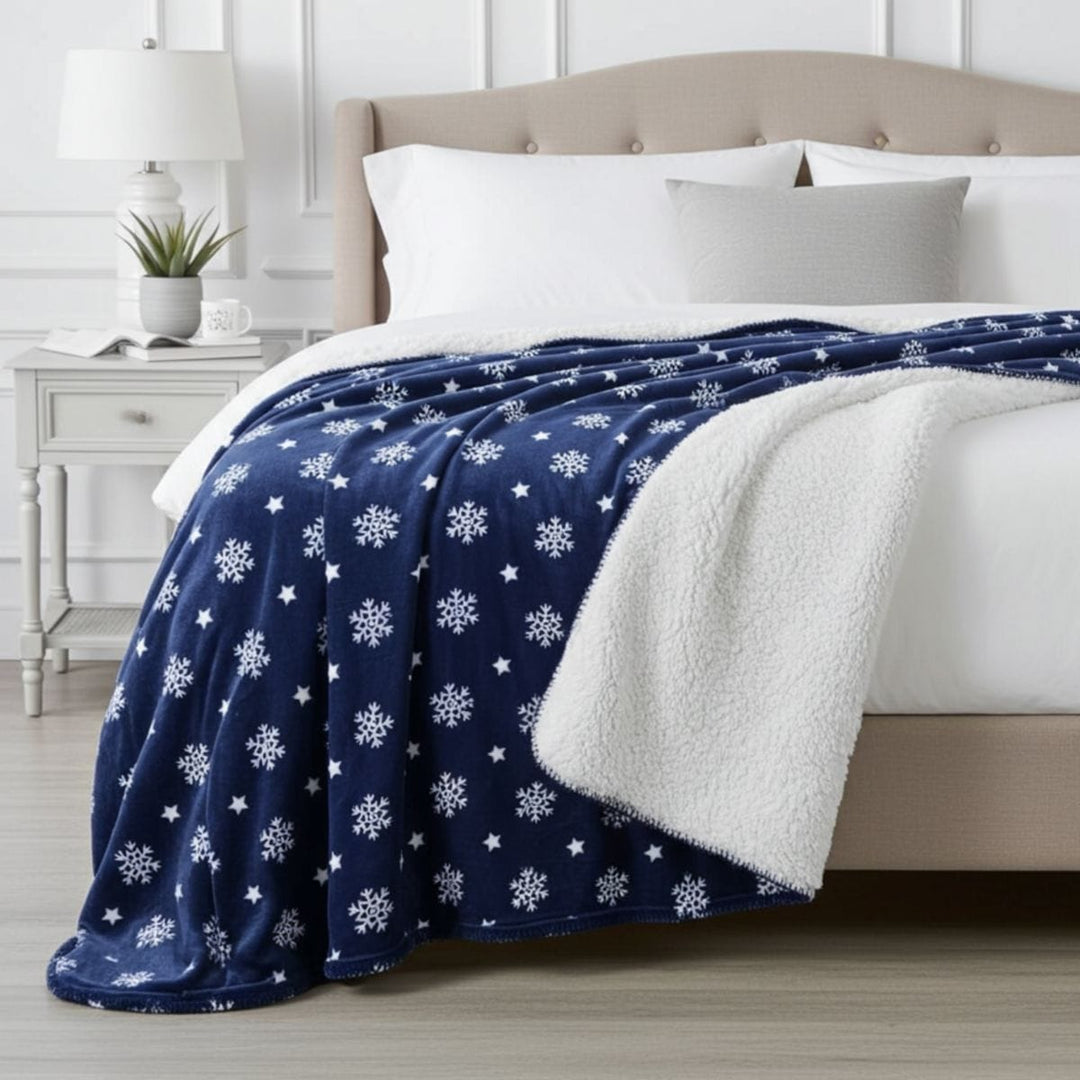 Blue blanket with white snowflake pattern draped over a bed in a bedroom setting.