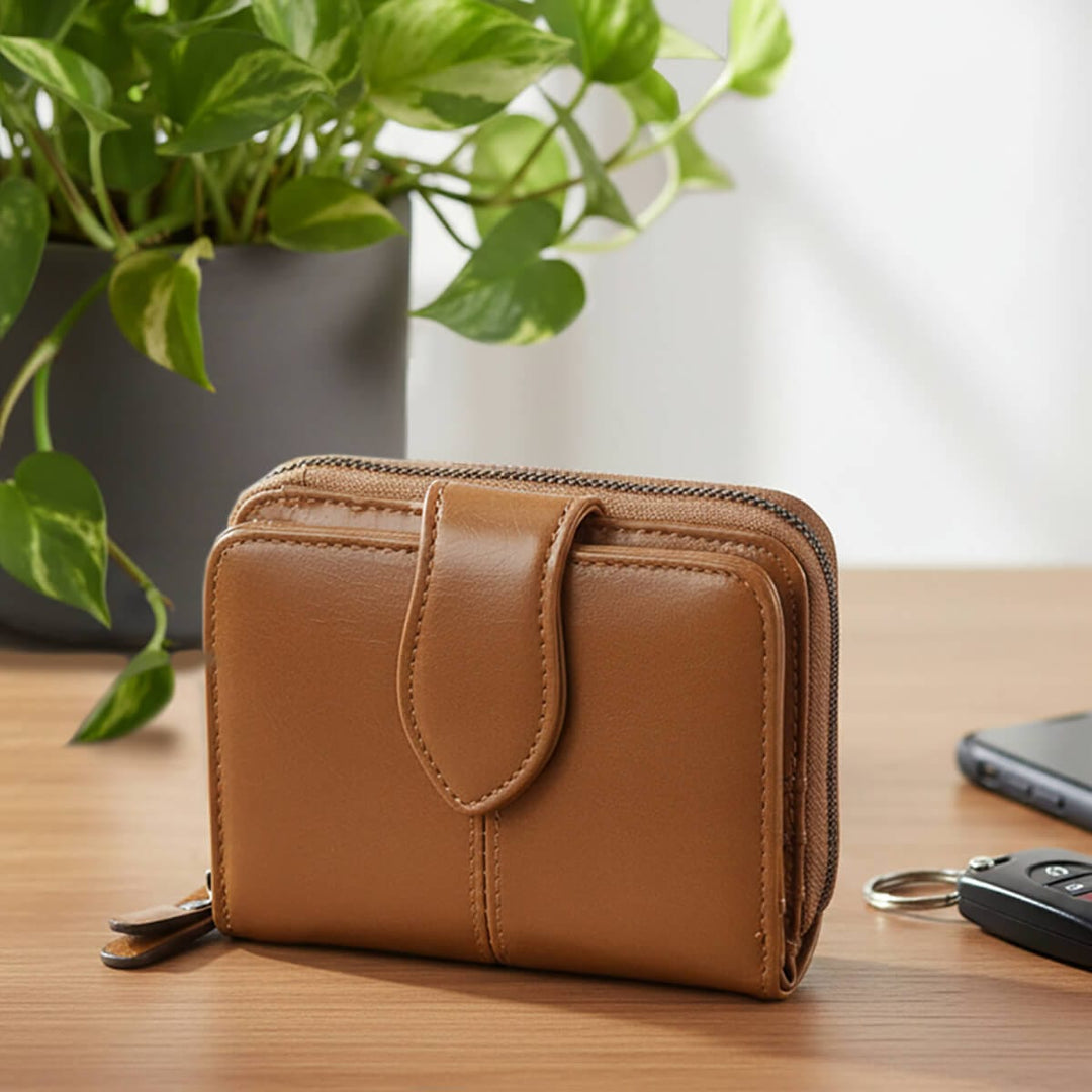 Tan colour leather purse on a table with car key mobile phone and houseplant