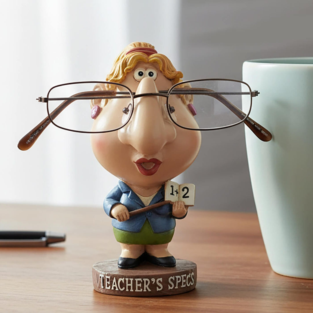 Teacher's Specs novelty figure glasses holder on a desk with blue coffee mug