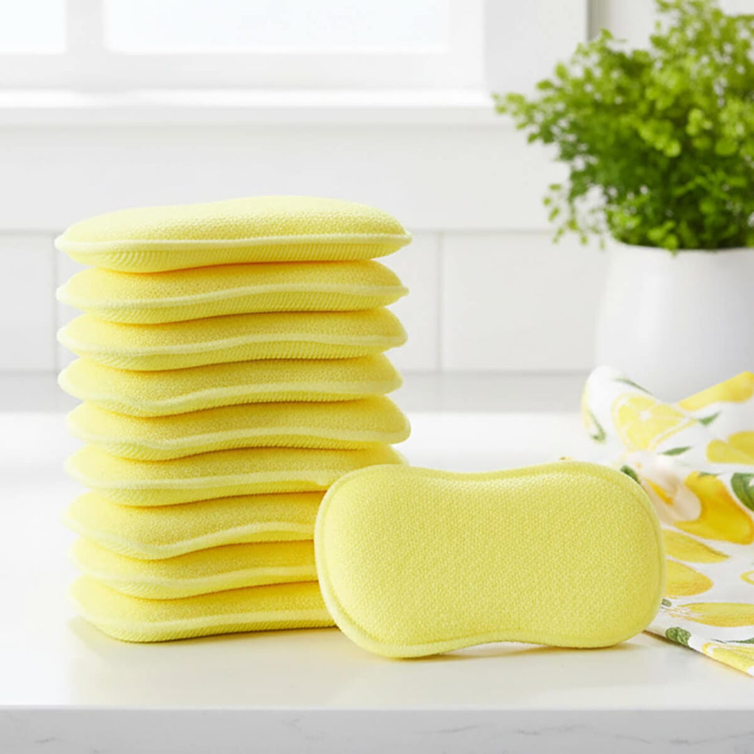 Stack of yellow cleaning pads on a white surface with a plant in the background