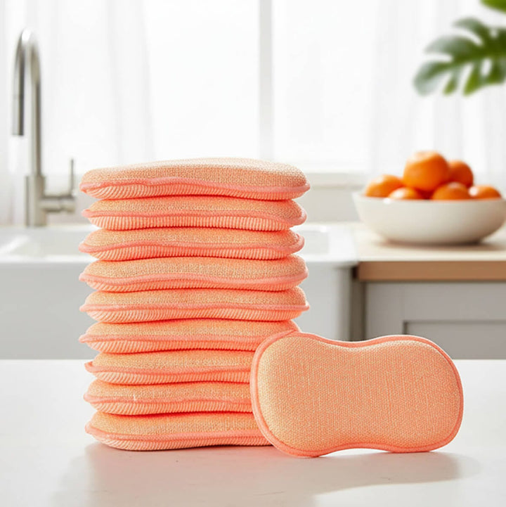 Stack of 10 orange cleaning pads on a kitchen table with bowl of oranges and plant in the background