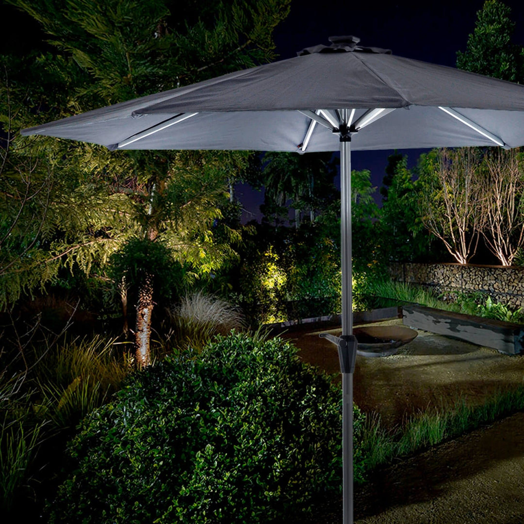 Silver grey LED parasol illuminated at night in a garden setting