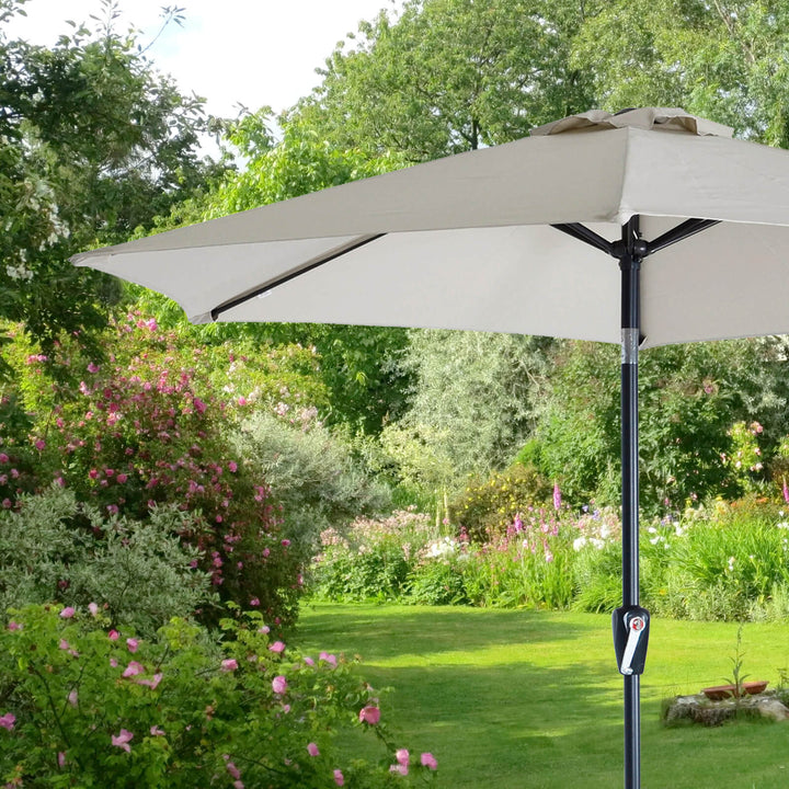Small silver garden parasol with crank handle and tilt button with garden setting