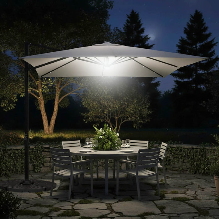 Outdoor patio table with chairs under a large parasol with LED lights at night.