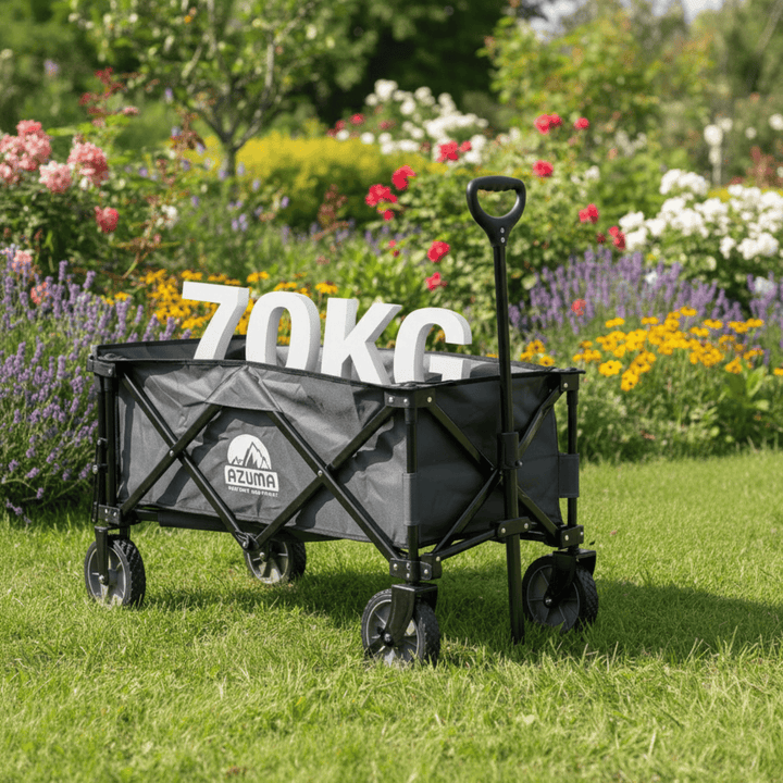 Black folding wagon with gray cover on grass in a garden setting, featuring &