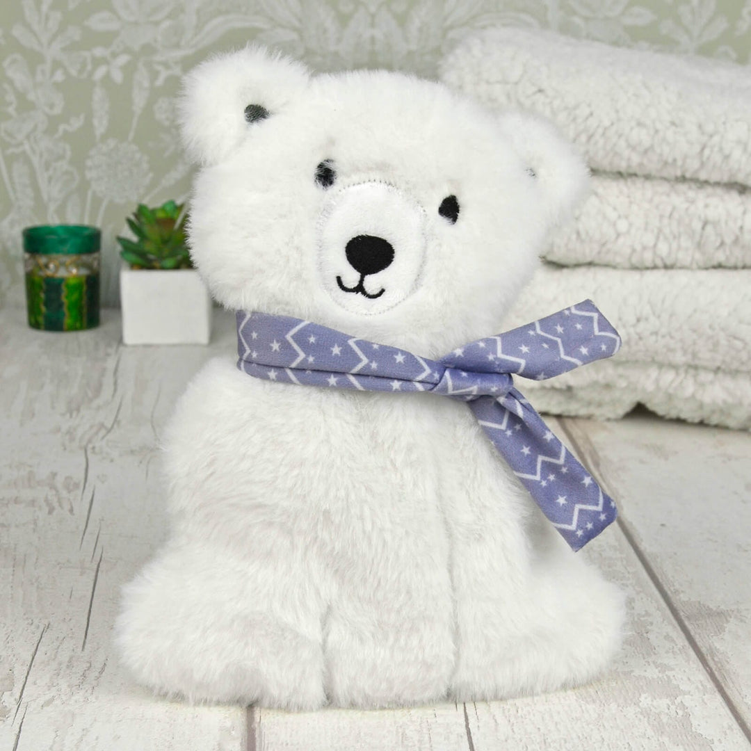 Plush polar bear heat pack on a whitewashed table with small plants and fleece blankets