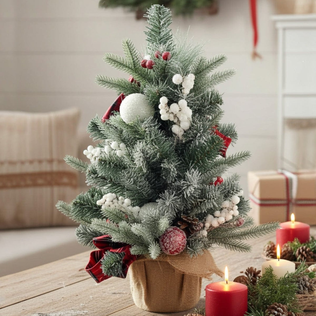 Decorated Christmas tree with red ribbons and white berries on a wooden table.