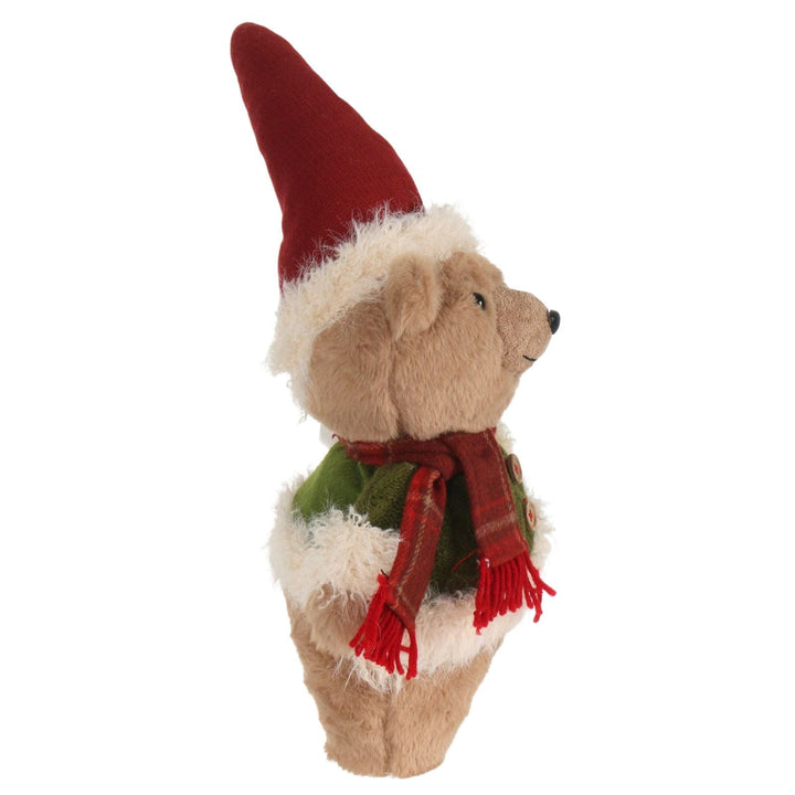 side view of stuffed bear with a red hat and scarf on a white background