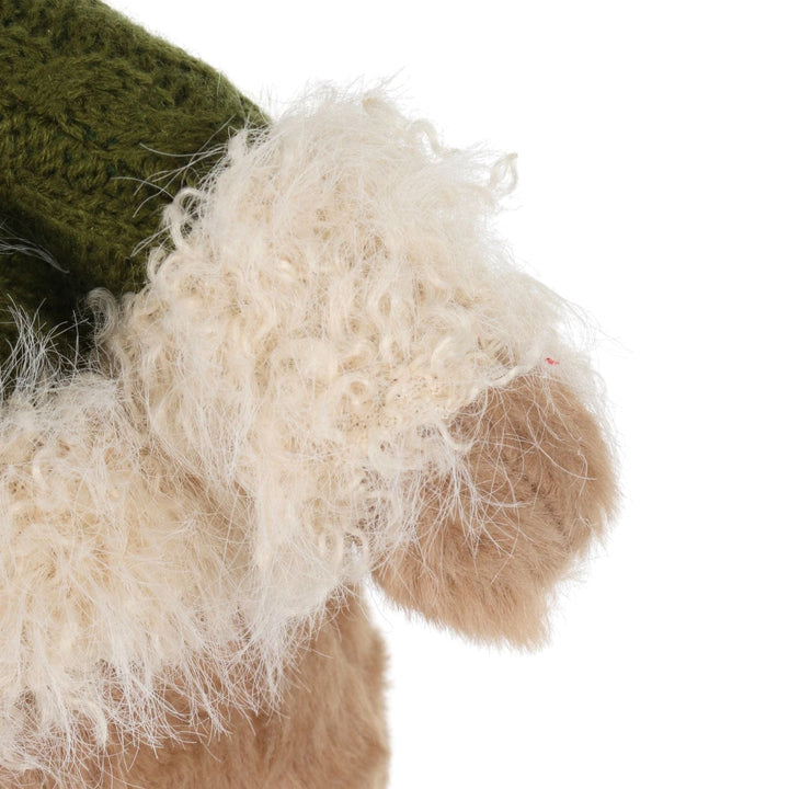 Close-up of a plush bear arm with white fur and green jumper on a white background