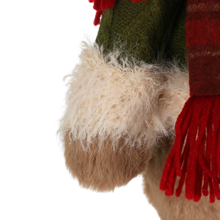 Close-up of a plush bear with green top, beige bottom, and red scarf on a white background