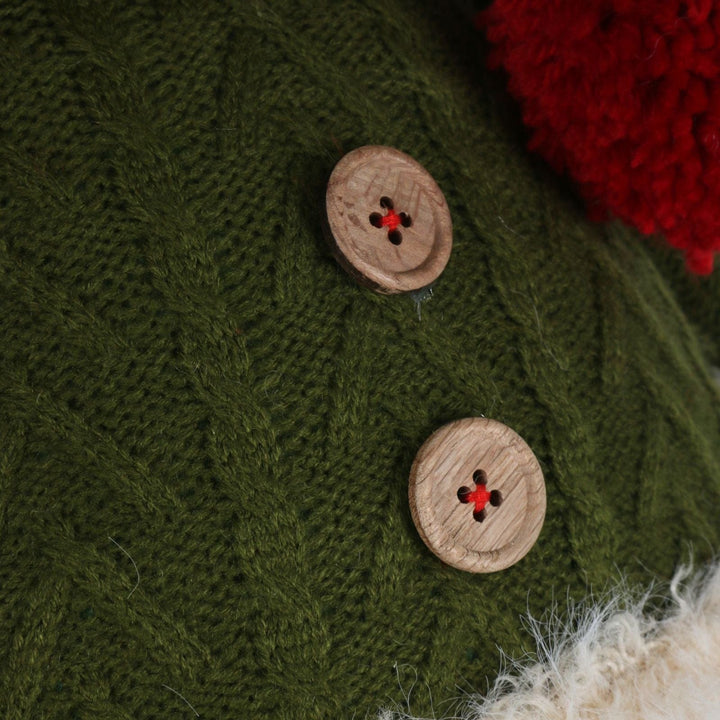 Close-up of a green knitted fabric with wooden buttons and red centers.