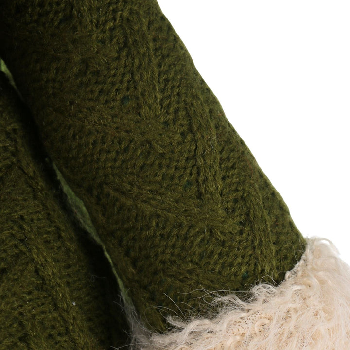 Close-up of a green knitted garment with a white fur trim on a white background