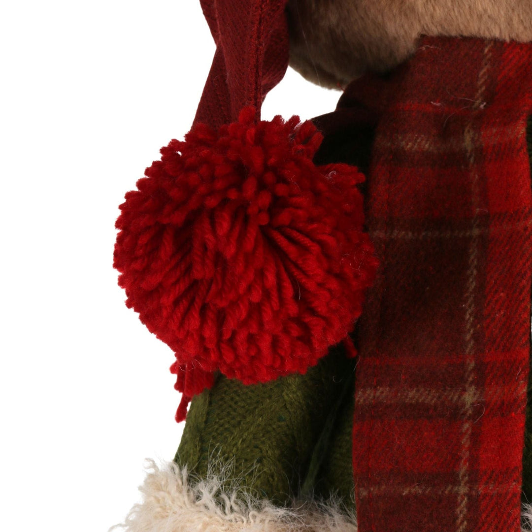 Close-up of a red plaid scarf with a large red pom-pom on a white background