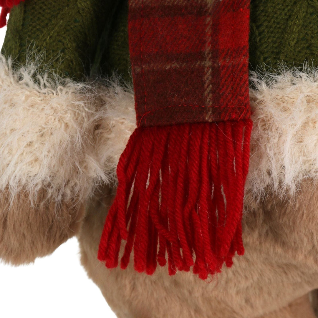 Close-up of a red plaid scarf with fringes on a fluffy surface.