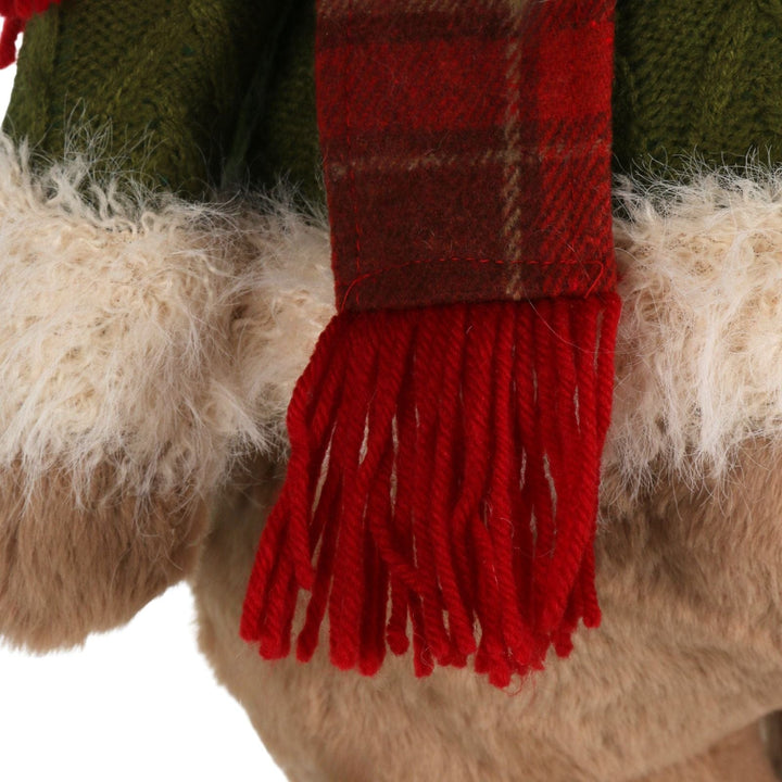 Close-up of a red plaid scarf with fringes on a fluffy surface.