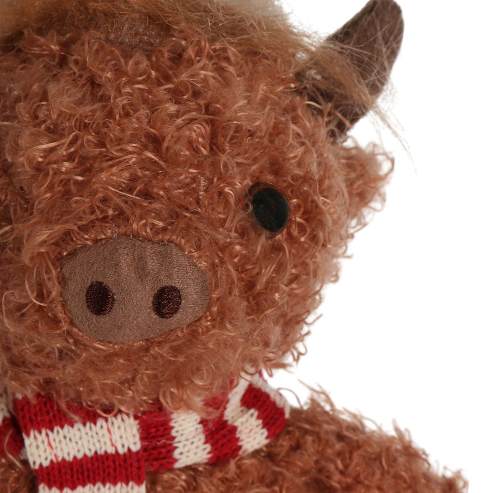 detail shot of stuffed highland cow decoration with plush embroidered nose and red and white striped scarf