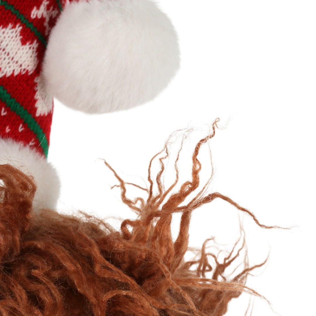 Close-up of a knitted red and white hat with a fluffy brown animal toy on a white background