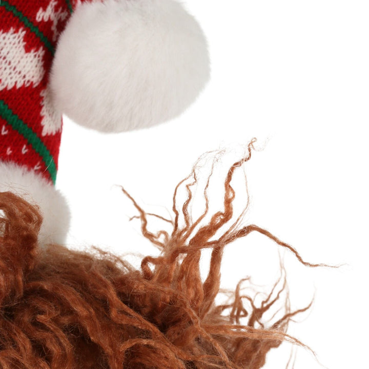 Close-up of a knitted red and white hat with a fluffy brown animal toy on a white background