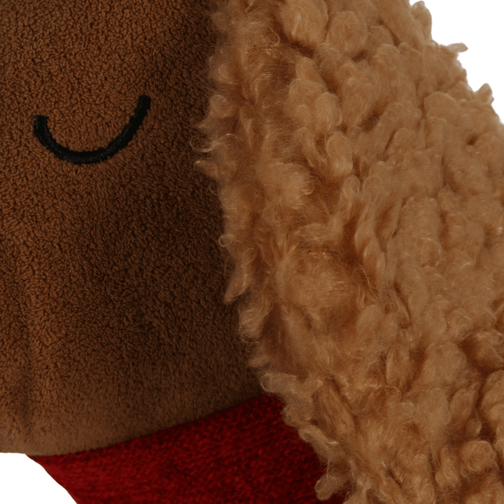 Close-up of a plush dog cushion with brown face and red scarf