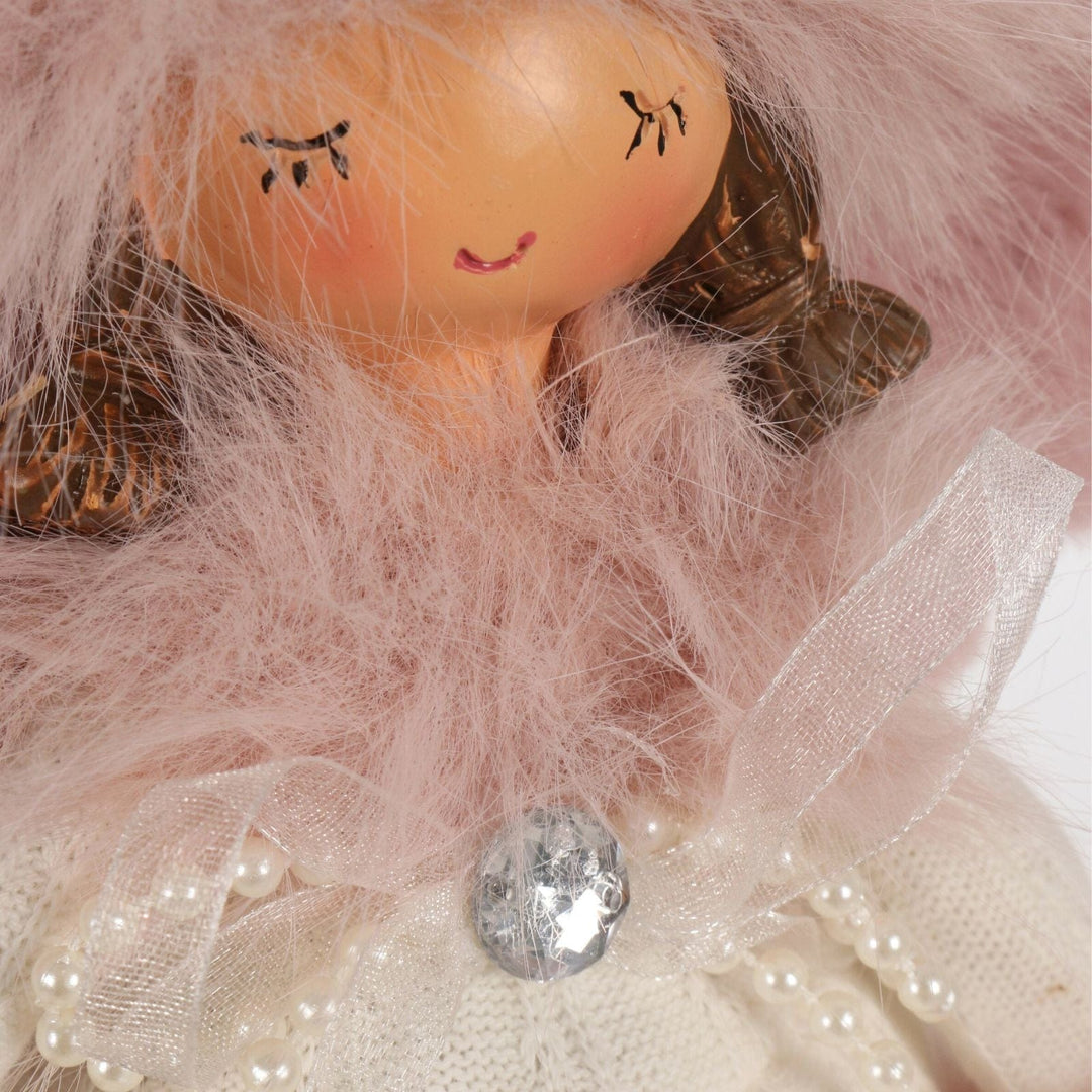 Close-up of a doll with pink hair and a white dress, surrounded by pink tulle.