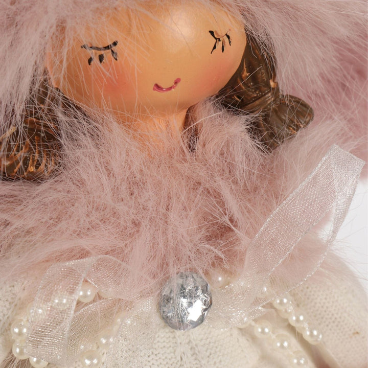 Close-up of a doll with pink hair and a white dress, surrounded by pink tulle.