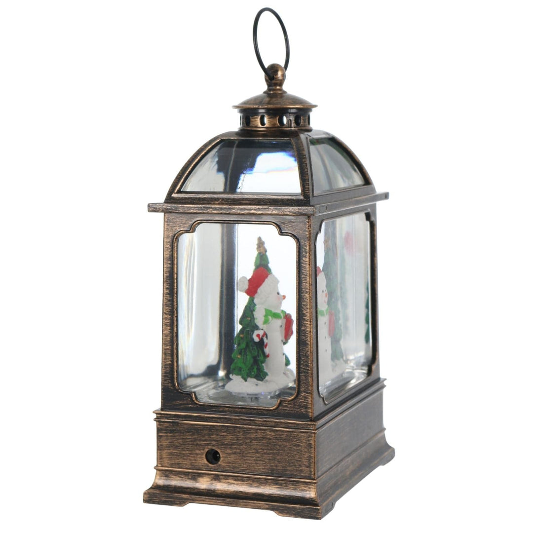 side view of decorative lantern with Christmas scene inside on a white background, and mains jack