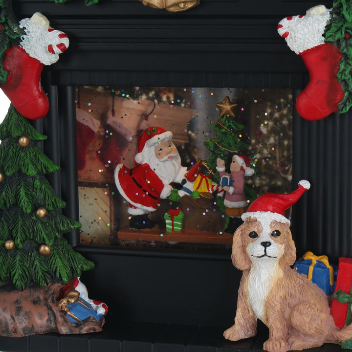 Decorative scene with Santa Claus, dog, Christmas tree, and stockings inside of a fireplace.