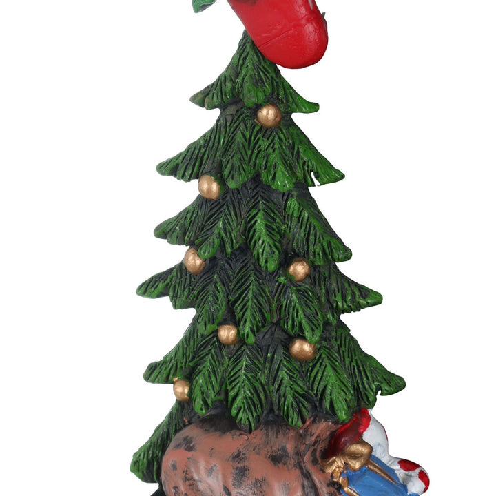 Decorative Christmas tree figurine with gold balls and a bag of gifts at the base on a white background