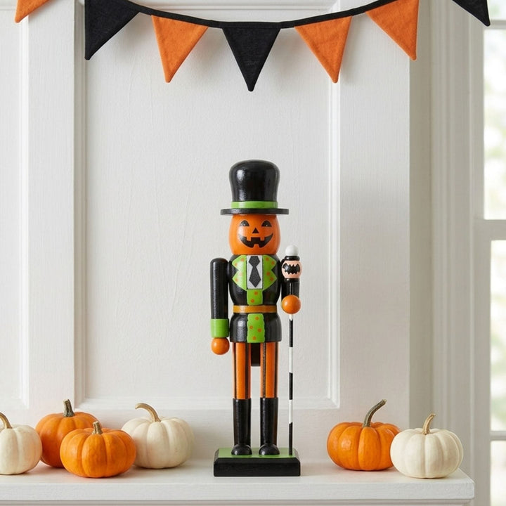 pumpkin nutcracker decoration on fireplace ledge beside mini pumpkins with orange and black bunting to the top