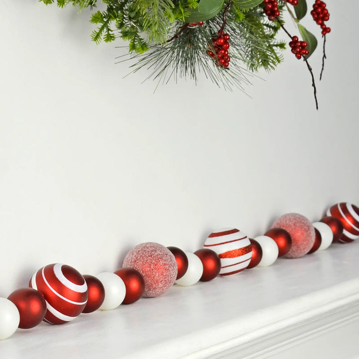 Decorative Christmas garland with assorted size red and white baubles on a fireplace mantel.