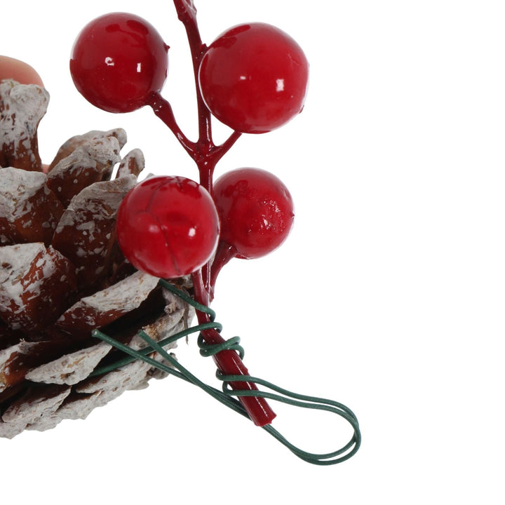 Decorative item with red berries and a pine cone on a white background