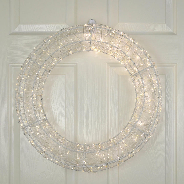 Decorative Christmas wreath with lights on a white wooden door