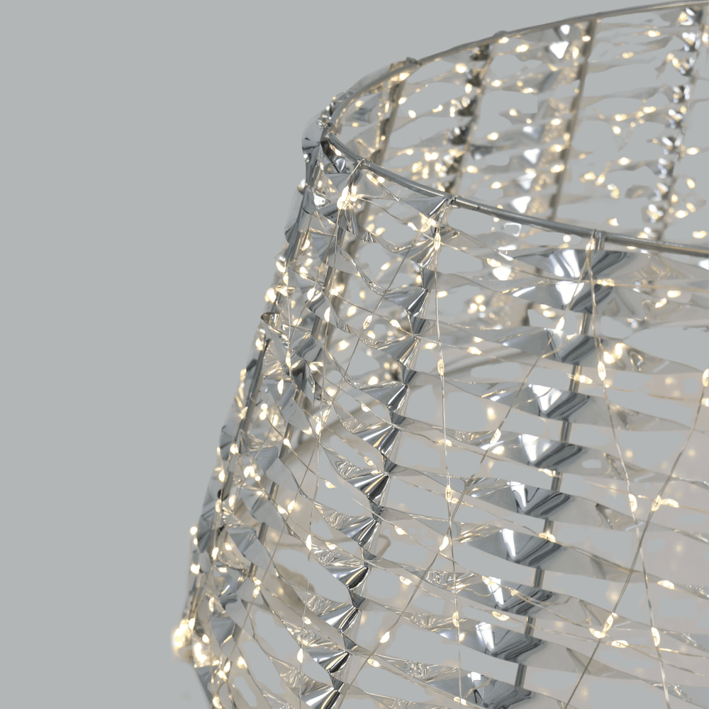 close up of copper wire warm white lights on tree skirt with silver PET material