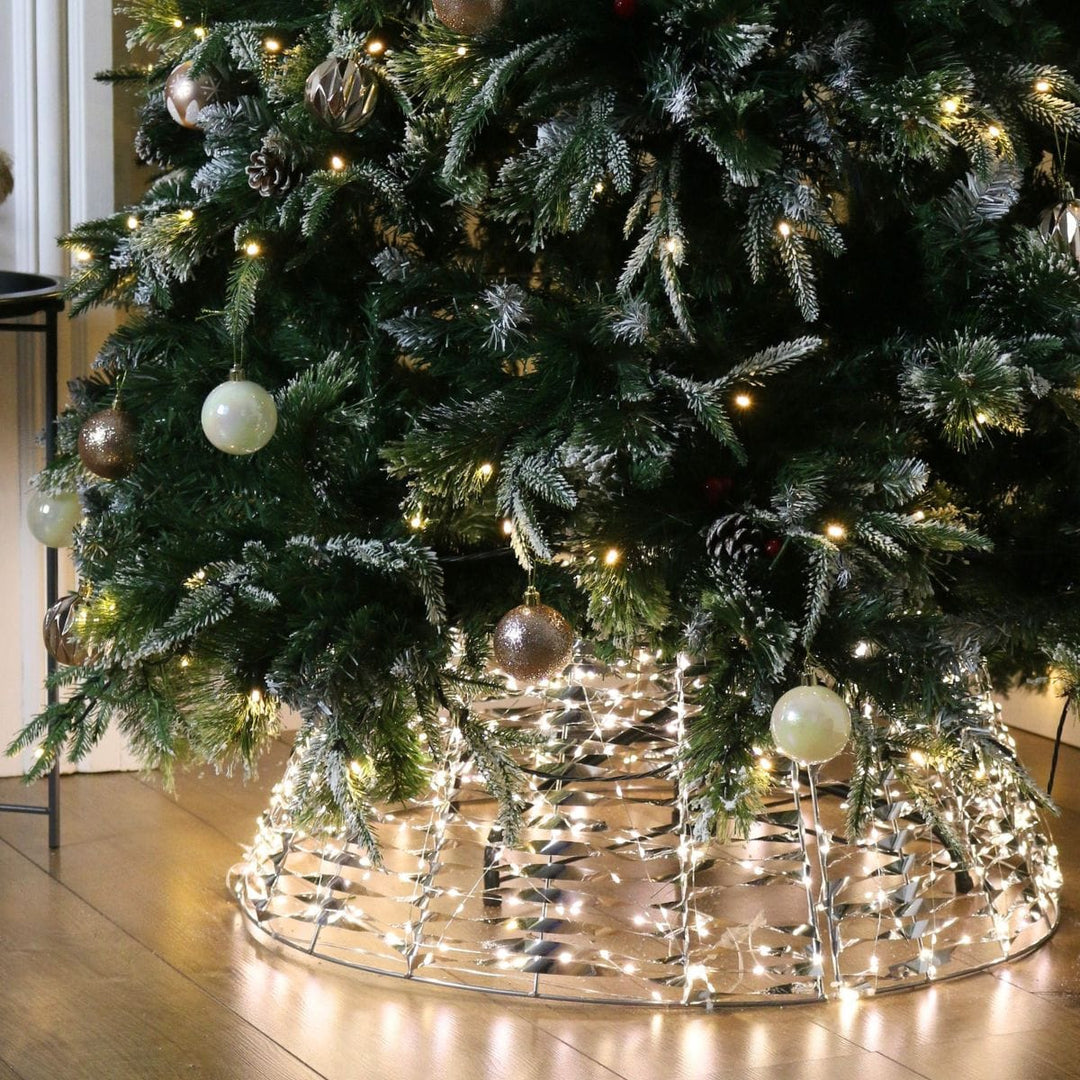 light up tree skirt on wooden floor with christmas tree inside featuring champagne colour baubles