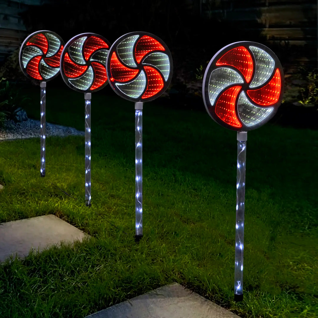 Set of 4 red and white Christmas infinity mirror pathway lights in a garden at night