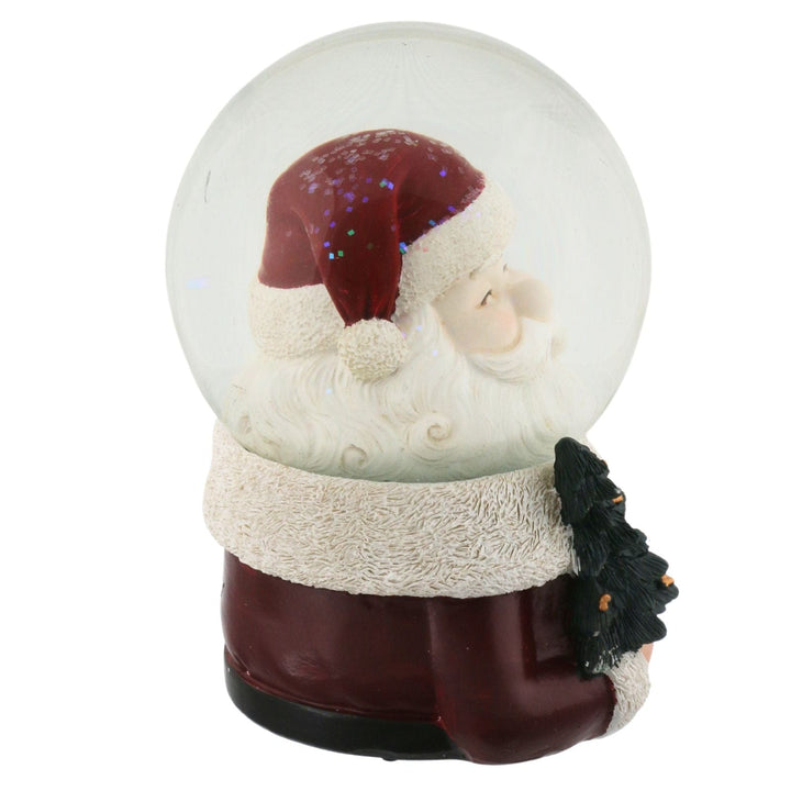 side view of snow globe with a Santa Claus figure inside on a white background