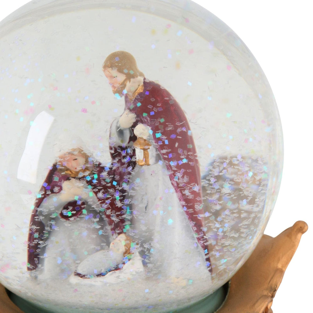 Snow globe with a nativity scene featuring mary, joseph and baby jesus with snow swirling inside