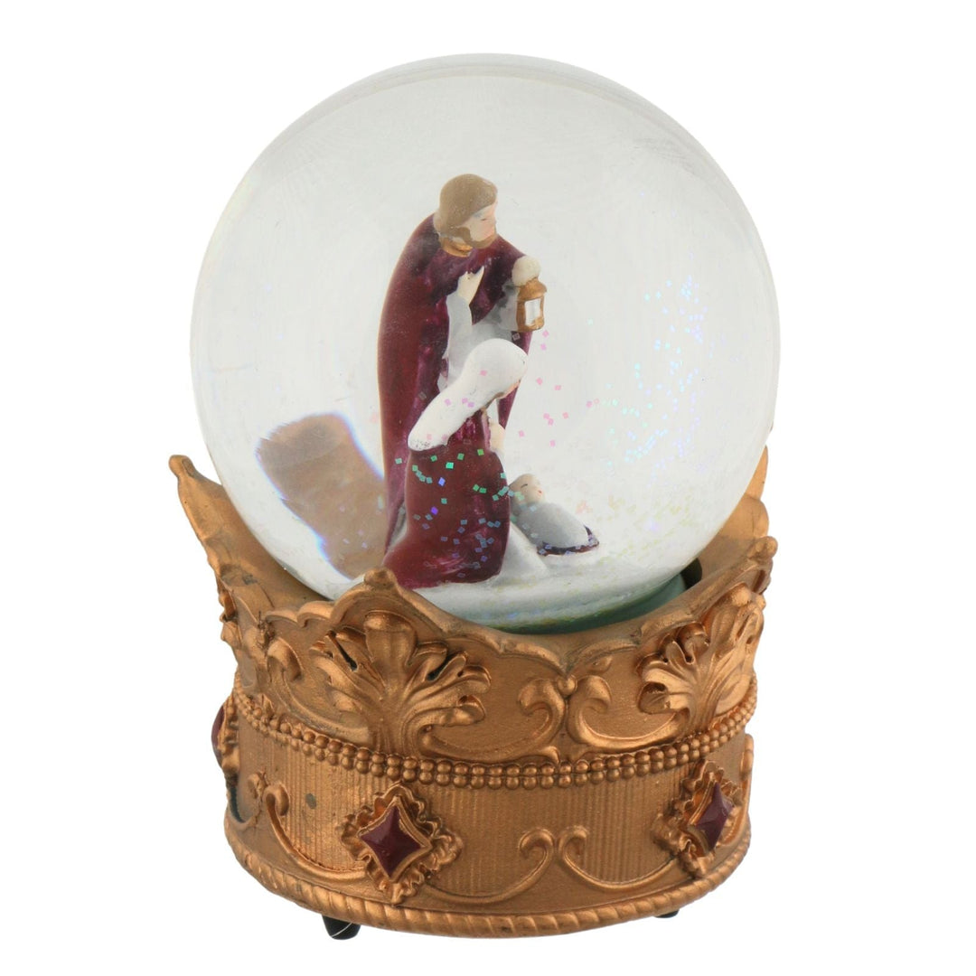Decorative snow globe with a gold base featuring a nativity scene inside.