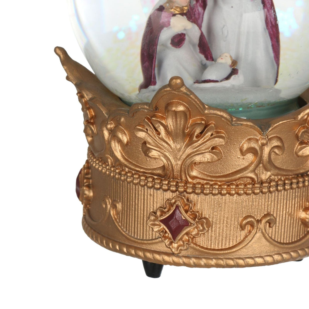 Decorative gold base with a glass sphere containing a nativity scene on a white background