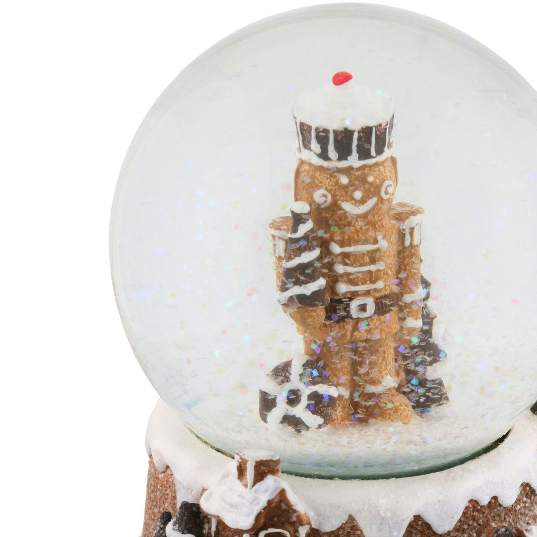 close up of gingerbread nutcracker inside snow globe with glittery snow moving around