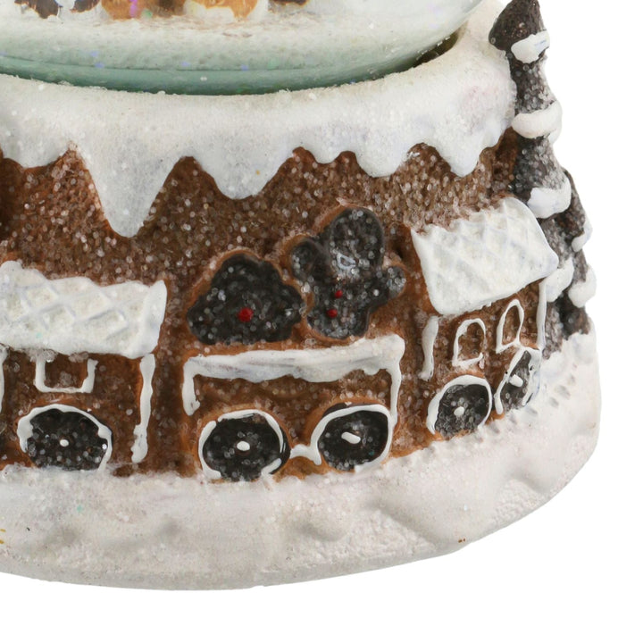 Gingerbread house-shaped candle with snow-like texture on a white background
