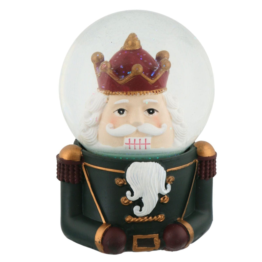 Snow globe with a nutcracker character wearing a crown and green outfit on a white background