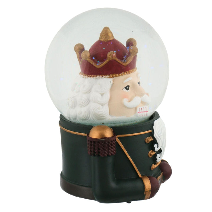 side view of nutcracker snow globe wearing red and gold crown