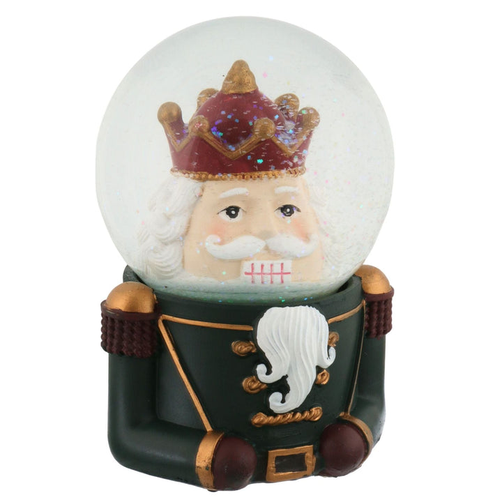 Snow globe with a nut cracker character wearing a crown and green outfit on a white background with glitter moving inside
