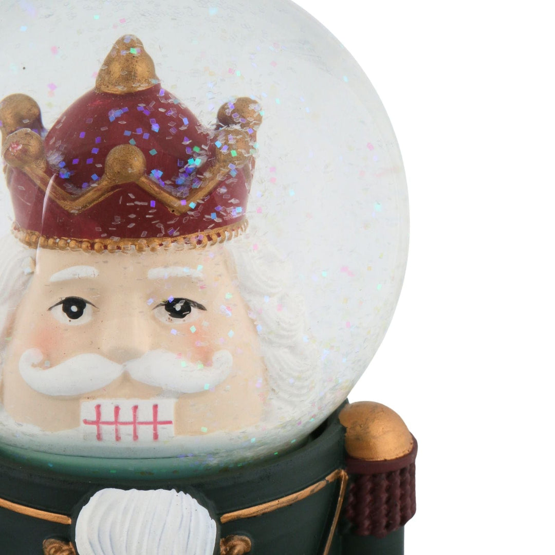 Snow globe with a nutcracker character wearing a crown on a white background